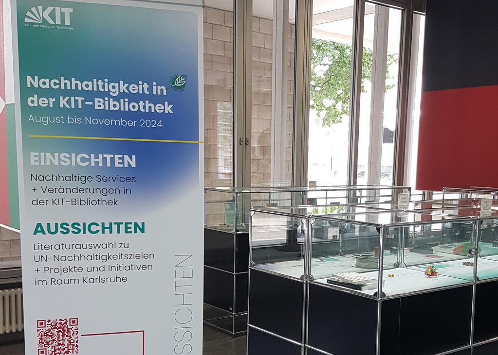 Auf der linken Seite steht der Rollup zu der Ausstellung zu Nachhaltigkeit in der KIT Bibliothek und rechts stehen erste Ausstellungsstücke.