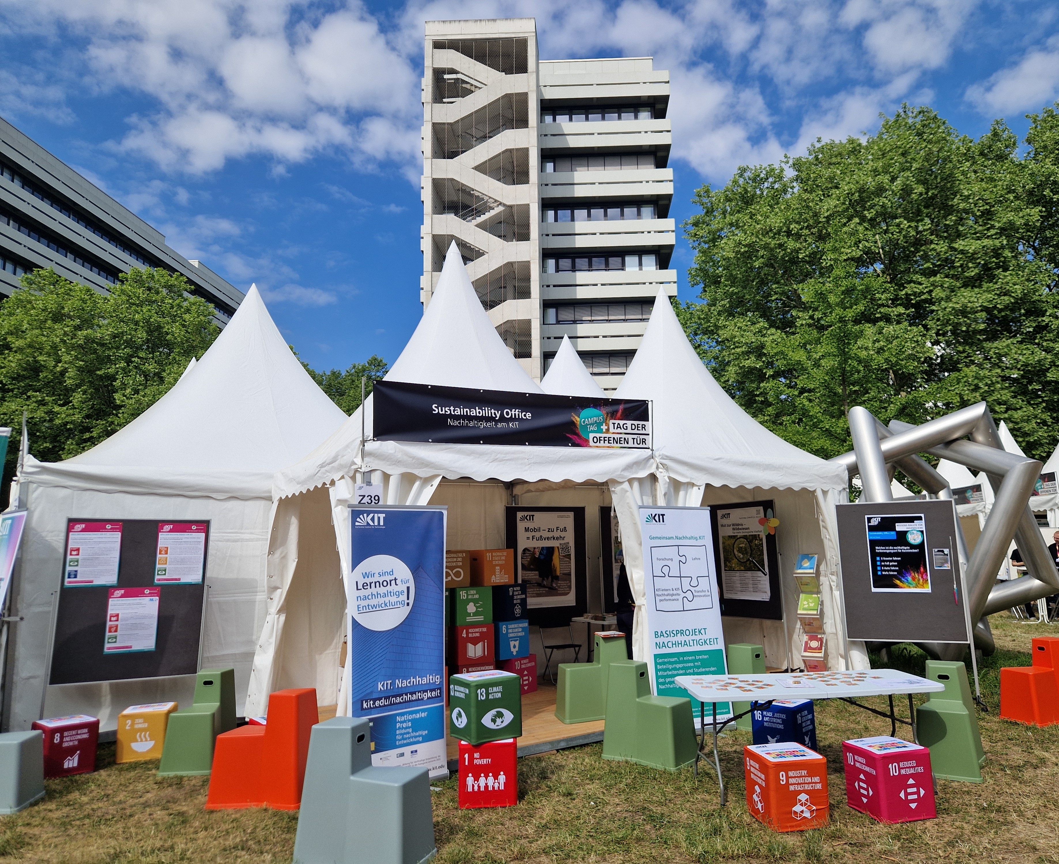 Zelt des Nachhaltigkeitsbüros beim Tag der offenen Tür, KIT, mit Infotafeln und Sitzwürfeln.